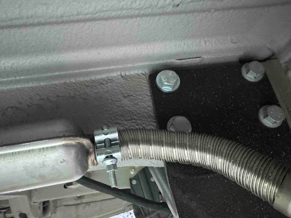 Metallic hose and bracket on a mechanical component, likely part of a larger machine or vehicle.